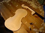 A violin back and a neck on the workbench